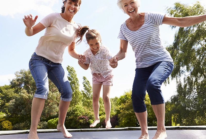 grandmother, mom and little girl jumping on trampoline