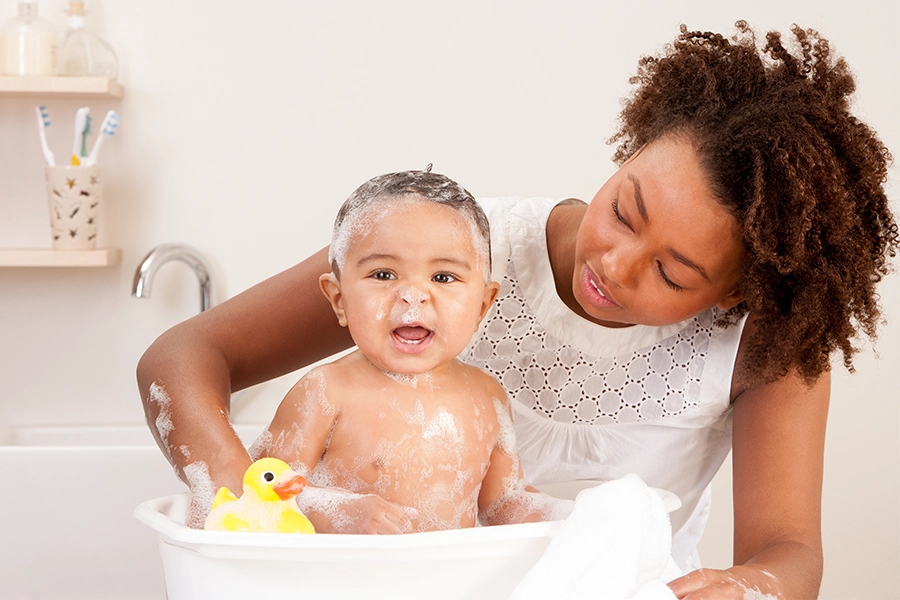 mom giving baby boy a bath and he was bubbles on head
